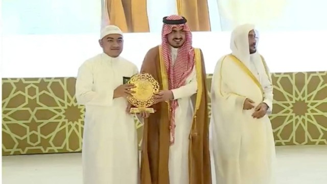 Momen Muhammad Mufid Al-Izza (kiri) menerima hadiah dari Wakil Emir Makkah Pangeran Bandar (tengah) didampingi Menteri Urusan Islam dalam MTQ Internasional di Arab Saudi, Kamis (7/9/2023). Foto: Twitter/@Saudi_Moia