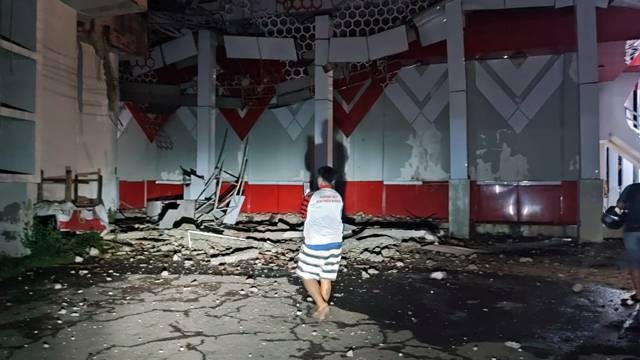 Seorang warga terlihat memandangi puing gedung GOR KONI Manado yang ambruk akibat gempa. (foto: febry kodongan)