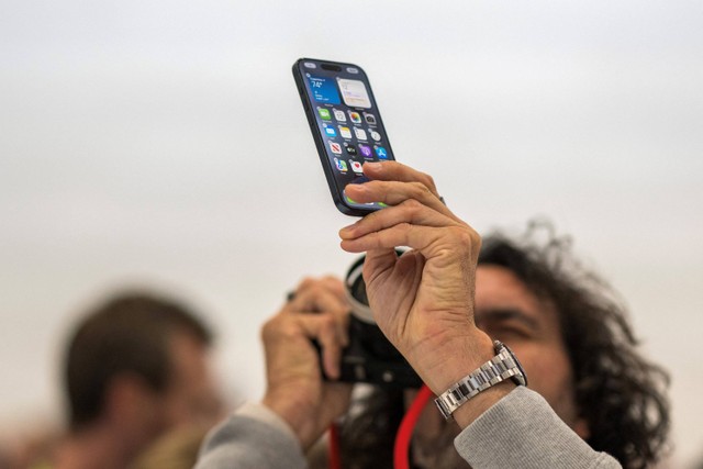 Pengunjung mencoba Apple iPhone 15 baru, dengan pengisi daya USB-C pesanan UE, ditampilkan di antara produk baru lainnya saat acara peluncuran di Apple Park di Cupertino, California, Selasa (12/9/2023). Foto: Nic Coury / AFP