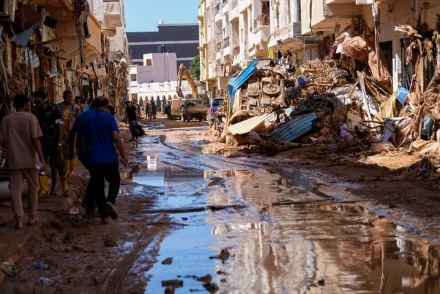 Orang-orang berjalan di lumpur di antara reruntuhan, setelah badai dahsyat dan hujan deras melanda Libya, di Derna, Libya, Rabu (13/9/2023). Foto: Esam Omran Al-Fetori/REUTERS