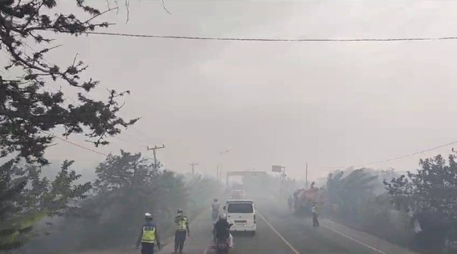 Suasana polisi sedang mengatur lalu lintas di Jalan Lintas Palembang-Indralaya yang terkepung asap karhutla, Foto : Manggala Agni