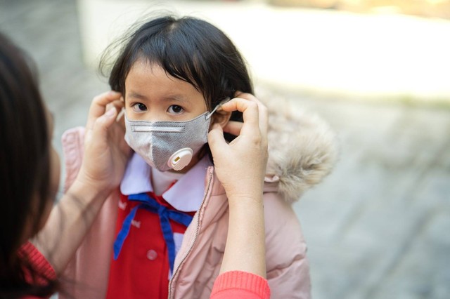 Seorang ibu sedang memakaikan masker pada anaknya. Foto: istimewa