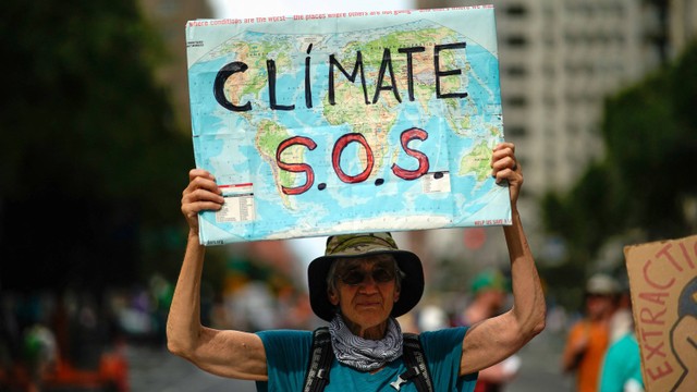 Seorang pria memegang poster saat unjuk rasa yang menyerukan pemerintah AS untuk mengambil tindakan terhadap perubahan iklim dan menolak penggunaan bahan bakar fosil di New York City. Foto: REUTERS/Eduardo Munoz