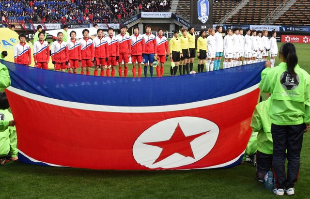 Pemain Korea Utara (kiri) menyanyikan lagu kebangsaan mereka sebelum pertandingan sepak bola wanita antara Korea Utara dan Korea Selatan pada kejuaraan sepak bola EAFF E-1 di Chiba pada 11 Desember 2017. Foto: Kazuhiro Nogi / AFP