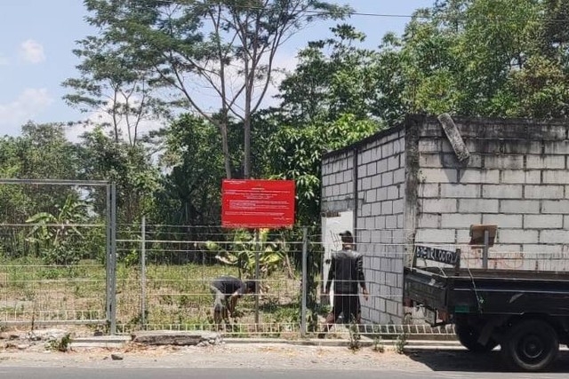 Petugas Kejati DIY memasang plakat penyitaan di tanah gratifikasi yang diterima eks Kepala Dispertaru DIY dari mafia tanah.  Foto: Dok. Kejati DIY