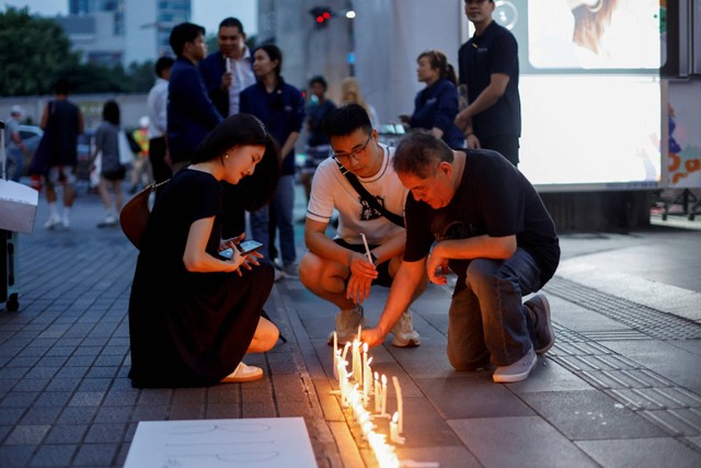 Warga meletakkan lilin di luar pusat perbelanjaan mewah Siam Paragon di Bangkok, Thailand, Rabu (4/10/2023). Foto: Jorge Silva/Reuters