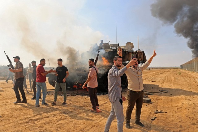 Warga Palestina menguasai tank Israel setelah melintasi pagar perbatasan dengan Israel dari Khan Yunis di Jalur Gaza selatan, Minggu (7/10/2023). Foto: Said Khatib/AFP