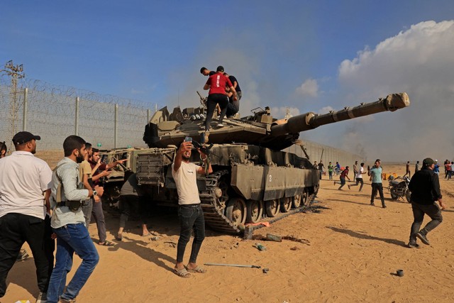 Warga Palestina menguasai tank Israel setelah melintasi pagar perbatasan dengan Israel dari Khan Yunis di Jalur Gaza selatan, Minggu (7/10/2023). Foto: Said Khatib/AFP