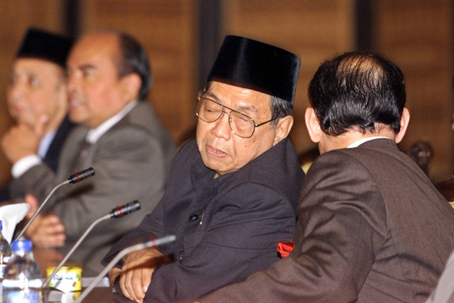 Presiden Abdurrahman Wahid (Gus Dur) berbicara dengan Menteri Luar Negeri Alwi Shihab setelah tiba di gedung parlemen di Jakarta, pada 27 April 2000. Foto: OKA BUDHI / AFP