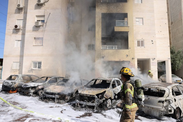 Tim pemadam kebakaran Israel memadamkan api di tempat parkir di luar sebuah bangunan tempat tinggal menyusul serangan roket dari Jalur Gaza di kota Ashkelon, Israel, Sabtu (7/10/2023).  Foto: AHMAD GHARABLI / AFP