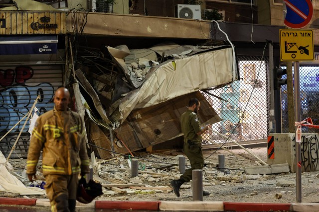 Petugas penyelamat berjalan di dekat reruntuhan usai serangan roket dari Jalur Gaza di Tel Aviv, Israel, Sabtu (7/10/2023).  Foto: JACK GUEZ / AFP