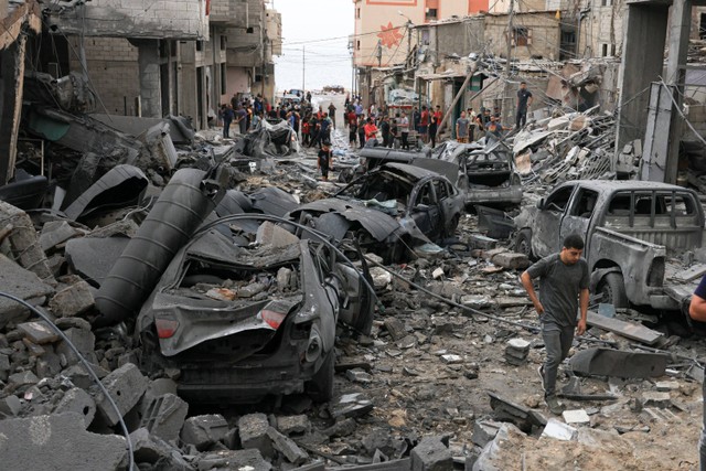 Warga Palestina memeriksa kehancuran di lingkungan yang rusak parah akibat serangan udara Israel di kamp pengungsi Shati Kota Gaza, Senin (9/10/2023). Foto: MAHMUD HAMS / AFP