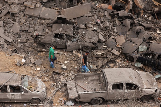 Warga Palestina memeriksa kehancuran di lingkungan yang rusak parah akibat serangan udara Israel di kamp pengungsi Shati Kota Gaza, Senin (9/10/2023). Foto: MAHMUD HAMS / AFP