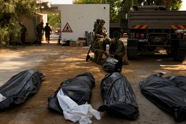 Tentara Israel berdiri di samping mayat warga Israel yang dibunuh oleh militan Hamas di kibbutz Kfar Azza, Israel pada Selasa (10/10/2023). Foto: Ohad Zwigenberg/AP Photo