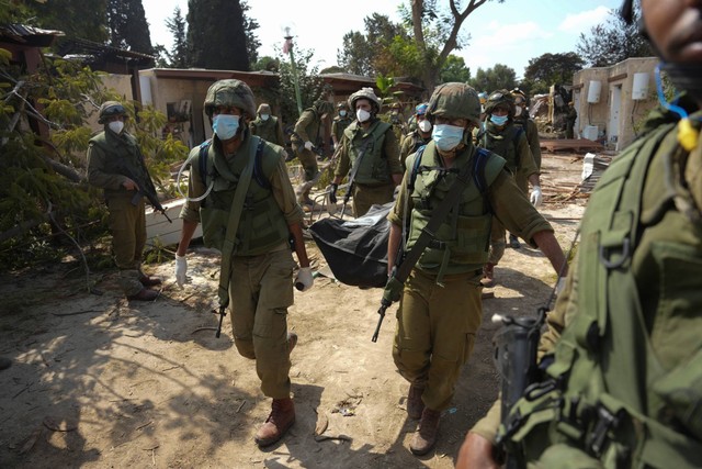 Tentara Israel membawa mayat warga Israel yang dibunuh oleh militan Hamas di kibbutz Kfar Azza, Israel pada Selasa (10/10/2023). Foto: Ohad Zwigenberg/AP Photo