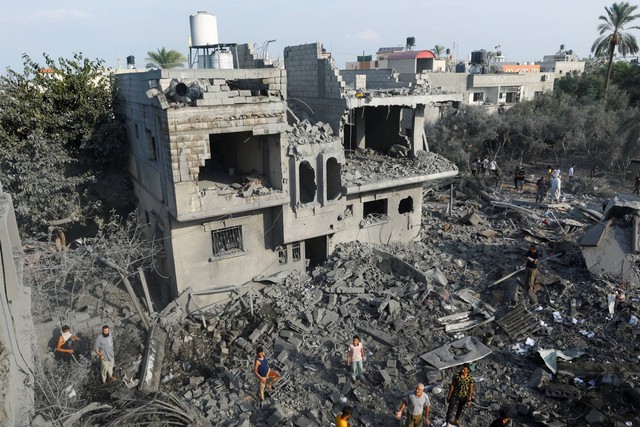 Warga Palestina berkumpul di puing-puing pasca serangan Israel, di Khan Younis di selatan Jalur Gaza, Rabu (11/10/2023). Foto: Ibraheem Abu Mustafa/REUTERS