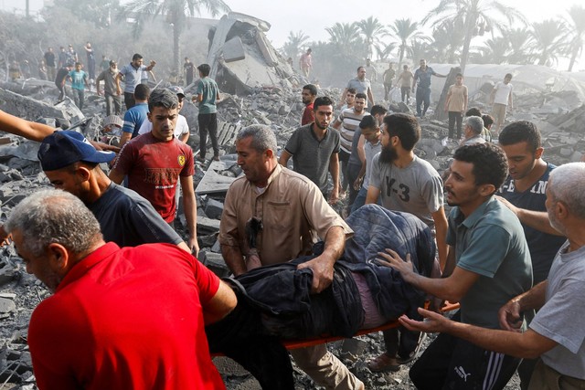 Warga Palestina membawa korban di lokasi serangan Israel terhadap rumah-rumah, di Khan Younis di selatan Jalur Gaza, Rabu (11/10/2023). Foto: Ibraheem Abu Mustafa/REUTERS