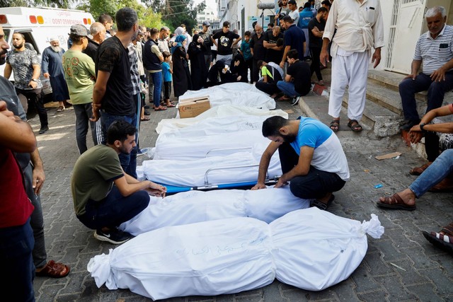 Keluarga dan kerabat berduka di samping jenazah warga Palestina yang tewas dalam serangan Israel, di sebuah rumah sakit di Kota Gaza, Rabu (11/10/2023). Foto: Mohammed Salem/REUTERS