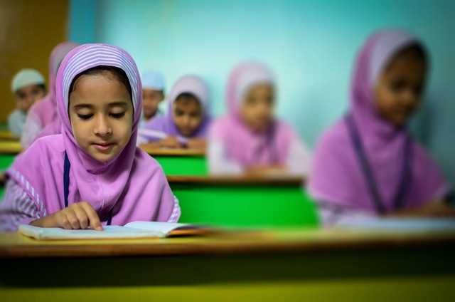 Anak perempuan terlihat sedang membaca Al-qur'an. Sumber: Pexels