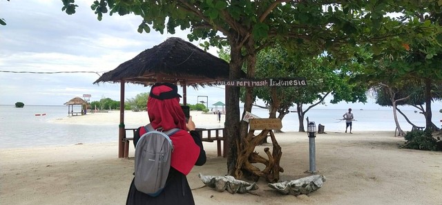 Seorang wisatawan sedang mengabadikan keindahan Pantai Pasir Perawan Pulau Pari. Foto: dok pribadi.