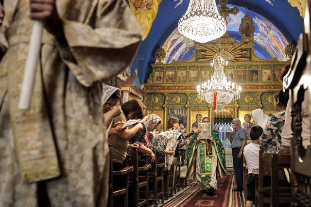 Seorang pendeta Ortodoks Yunani berjalan melewati jamaah Kristen Palestina saat Misa Minggu di Gereja Saint Porphyrius di Kota Gaza, pada 30 Mei 2021. Foto: Thomas Coex / AFP