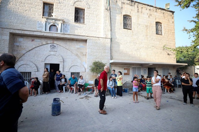 Warga Palestina berkumpul di Gereja Ortodoks Yunani Saint Porphyrius yang rusak akibat serangan Israel, tempat warga Palestina yang meninggalkan rumah mereka berlindung, di Kota Gaza, Jumat (20/10/2023). Foto: Mohammed Al-Masri/REUTERS