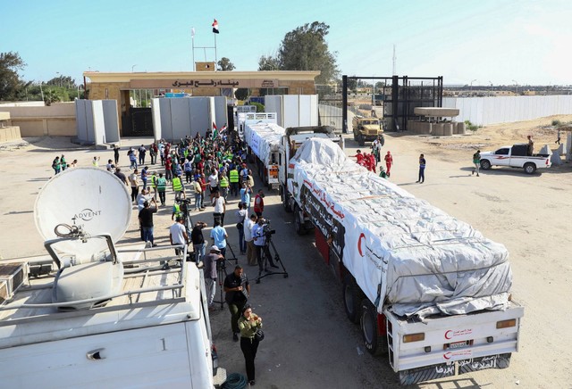 Relawan Mesir berkumpul dan merayakan di samping truk yang membawa bantuan kemanusiaan dari LSM Mesir yang melewati penyeberangan Rafah dari sisi Mesir, di Rafah, Mesir, Sabtu (21/10/2023). Foto: Stringer/REUTERS