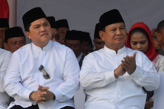Menteri Pertahanan Prabowo Subianto (kanan) dan Menteri BUMN Erick Thohir (kiri) menyimak pidato Presiden Joko Widodo saat apel Hari Santri Nasional di Tugu Pahlawan, Surabaya, Jawa Timur, Minggu (22/10/2023). Foto: Zabur Karuru/Antara Foto