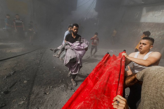 Seorang pria Palestina membawa korban anak-anak di lokasi serangan Israel terhadap rumah-rumah, di Khan Younis di Jalur Gaza selatan, Kamis (26/10/2023). Foto: Mohammed Salem/REUTERS