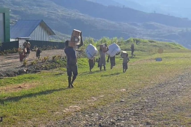 Sejumlah warga menurunkan bahan makanan dari pesawat terbang di Distrik Amuma, Kabupaten Yahukimo, Papua Pegunungan, Kamis (26/10/2023). Foto: Humas BNPB via Antara