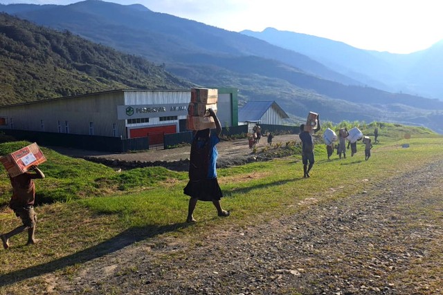 Sejumlah warga membawa bahan makanan yang diturunkan dari pesawat terbang di Distrik Amuma, Kabupaten Yahukimo, Papua Pegunungan, Kamis (26/10/2023). Foto: Humas BNPB/ANTARA FOTO