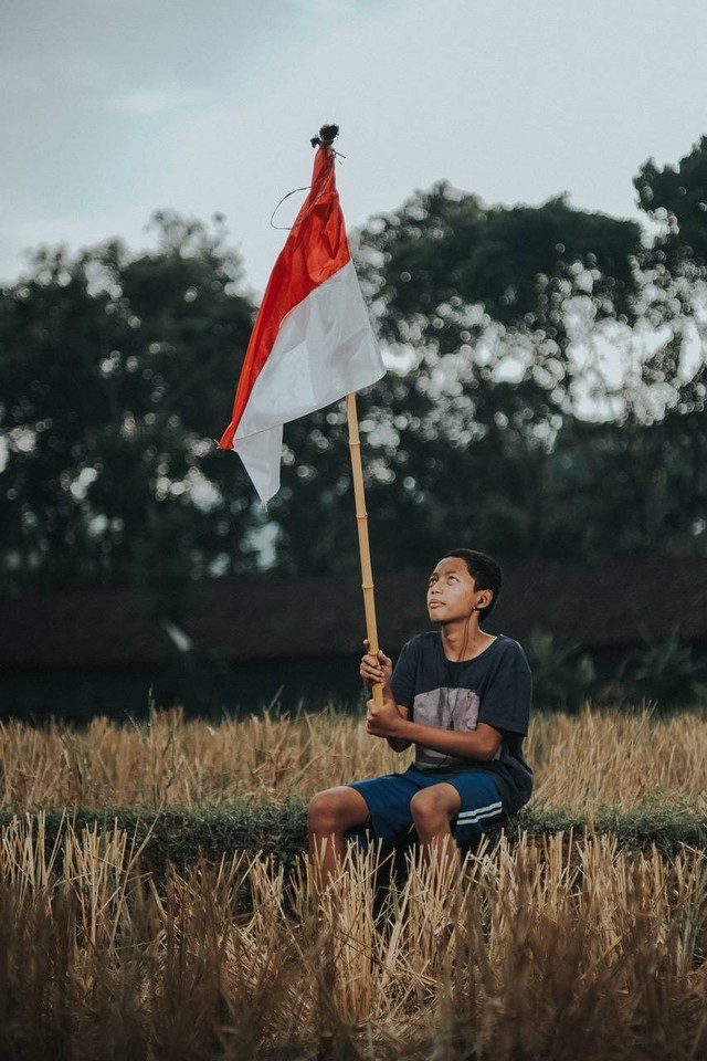 Ilustrasi pemuda memegang bendera Merah Putih. Foto: Pixabay