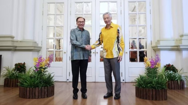 Perdana Menteri Malaysia Anwar Ibrahim (kiri) dan Perdana Menteri Singapura Lee Hsien Loong berjabat tangan pada Leaders' Retreat ke-10 di Singapura pada Senin (30/10/2023). Foto: Ministry of Communications and Information