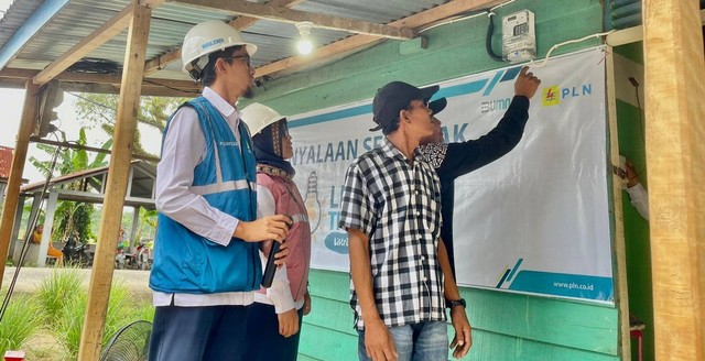 Salah satu penerima bantuan pasang baru gratis sedang menyalakan listrik. Foto: dok. PLN