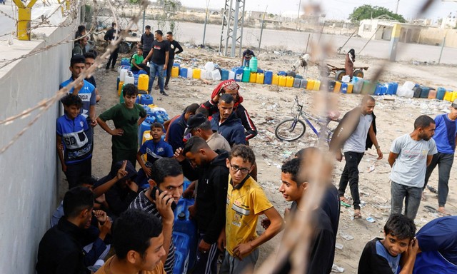 Sejumlah warga Palestina antre mengambil air di Rafah, selatan Jalur Gaza, Minggu (5/11/2023). Foto: Ibraheem Abu Mustafa/Reuters