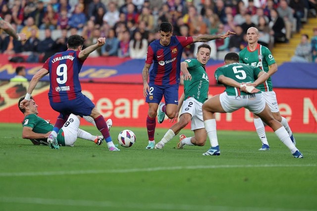 Joao Cancelo (tengah) berduel dengan Andoni Gorossabel dalam pertandingan Barcelona vs Alaves di Estadi Olimpic Lluis Companys, Barcelona, pada Minggi (12/11). Foto: Lluis Gene/AFP