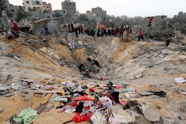 Warga Palestina berkumpul di lokasi serangan Israel, di tengah konflik yang sedang berlangsung antara Israel dan kelompok Palestina Hamas, di Khan Younis di selatan Jalur Gaza 12 November 2023. Foto: REUTERS/Ibraheem Abu Mustafa