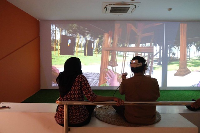 Seorang pengunjung dengan dipandu pegawai museum sedang memainkan simulasi jemparingan. Sumber: dokumentasi pribadi
