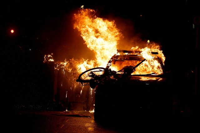 Sebuah mobil terbakar saat bentrokan di tengah protes usai insiden penikaman yang menyebabkan beberapa anak terluka di Dublin, Irlandia, kamis (23/11/2023). Foto: Clodagh Kilcoyne/REUTERS