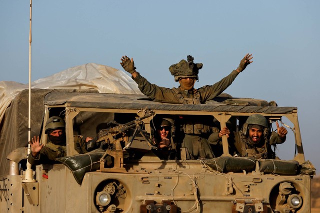 Tentara Israel bereaksi dari kendaraan militer saat berkendara di perbatasan Israel ketika meninggalkan Gaza, selama gencatan senjata, di Israel, Jumat (24/11/2023). Foto: Amir Cohen/REUTERS
