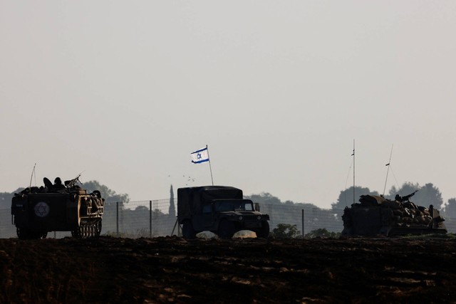 Konvoi tank militer Israel dan Pengangkut Personil Lapis Baja (APC) melewati perbatasan Israel setelah meninggalkan Gaza selama gencatan senjata, di Israel, Jumat (24/11/2023). Foto: Amir Cohen/REUTERS