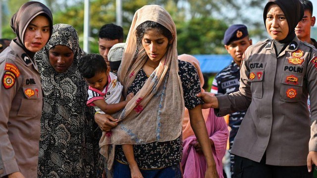Pengungsi Rohingya menaiki kapal feri di sebuah pantai di pulau Sabang, provinsi Aceh, Indonesia pada Rabu (22/11), saat mereka direlokasi oleh aparat keamanan.