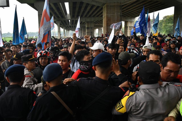 Sejumlah personel Kepolisian menahan buruh yang ingin menuju gerbang Tol Cibitung 3 di kawasan MM 2100, Kabupaten Bekasi, Jawa Barat, Kamis (30/11/2023). Foto: ANTARA FOTO/ Fakhri Hermansyah