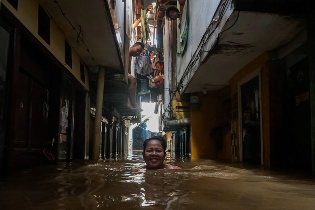 Seorang warga menerobos banjir yang merendam rumah di kawasan Kebon Pala, Kampung Melayu, Jakarta, Kamis (30/11/2023). Foto: Rifqi Raihan Firdaus/ANTARA FOTO