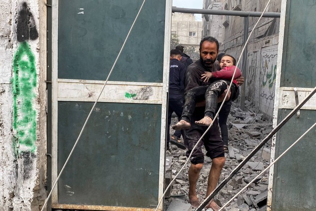 Seorang warga Palestina membawa seorang anak laki-laki yang terluka menyusul serangan Israel di sebuah rumah, setelah gencatan senjata sementara antara Hamas dan Israel berakhir, di Rafah, di selatan Jalur Gaza, Jumat (1/12/2023). Foto: Hatem Khaled/REUTERS