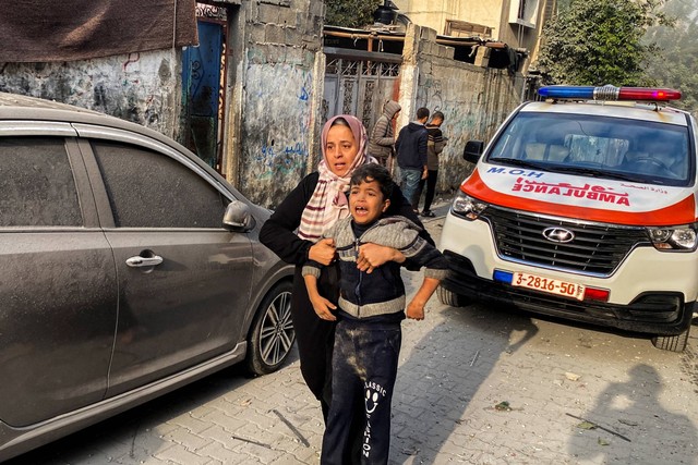 Seorang wanita Palestina membantu seorang anak yang terluka akibat serangan Israel di sebuah rumah, setelah gencatan senjata sementara antara Hamas dan Israel berakhir, di Rafah, di selatan Jalur Gaza, Jumat (1/12/2023). Foto: Hatem Khaled/REUTERS