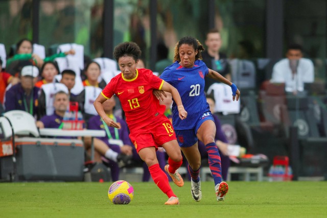 Penyerang Tiongkok Zhang Linyan (19) melindungi bola dari bek Amerika Serikat Casey Krueger (20) pada babak pertama di Stadion DRV PNK di Fort Lauderdale, Florida, AS. Foto:  Sam Navarro-USA TODAY Sports/Reuters