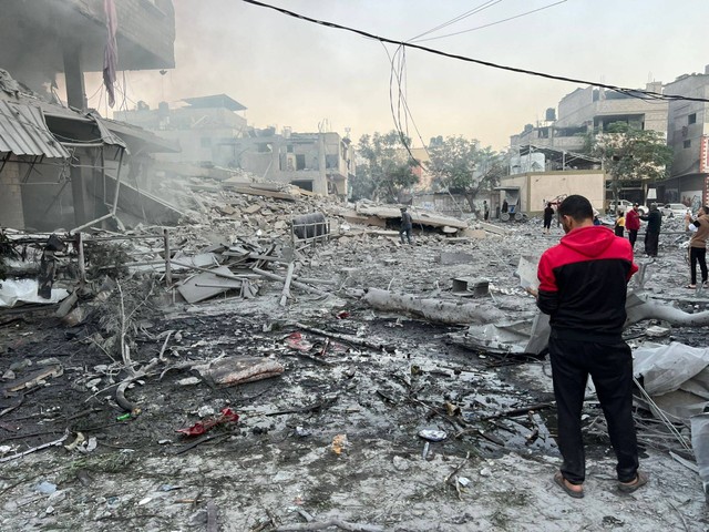 Warga Palestina terlihat di depan bangunan yang hancur usai serangan Israel yang menghantam kamp pengungsi Jabalia di Kota Gaza, Gaza pada Jumat (1/12/2023). Foto: Fadi Alwhidi/Anadolu via Reuters