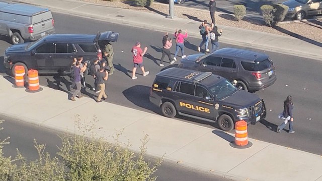 Orang-orang meninggalkan kampus dengan mengangkat tangan usai laporan penembakan di Universitas Nevada, di kampus Las Vegas, AS, Rabu (6/12/2023). Foto: Reuters