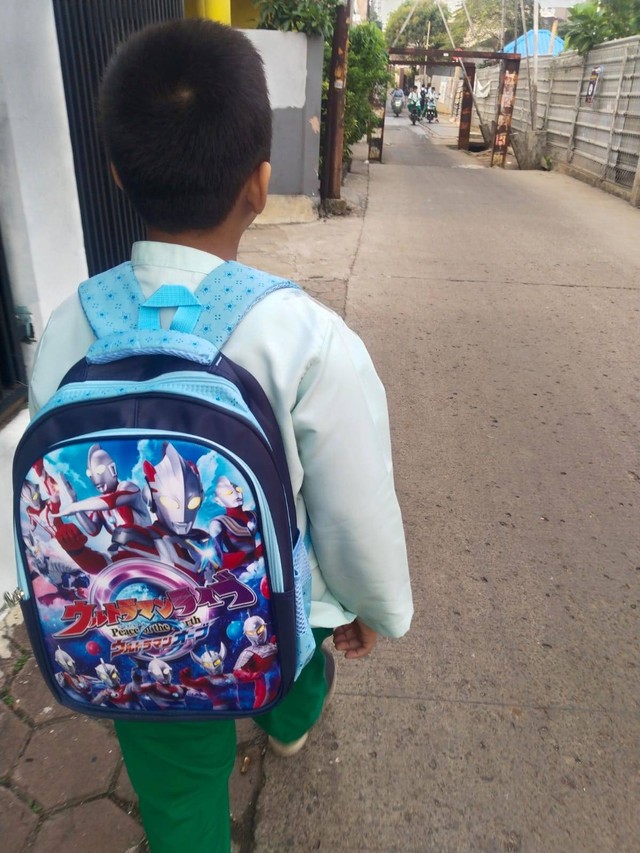 Seorang anak berangkat ke sekolah tidak ditemani oleh ayahnya yang jauh di kota lain. Photo: Dokumentasi Pribadi